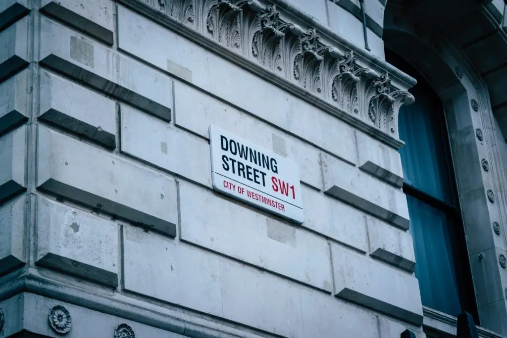 A Downing Street sign on a brick wall.