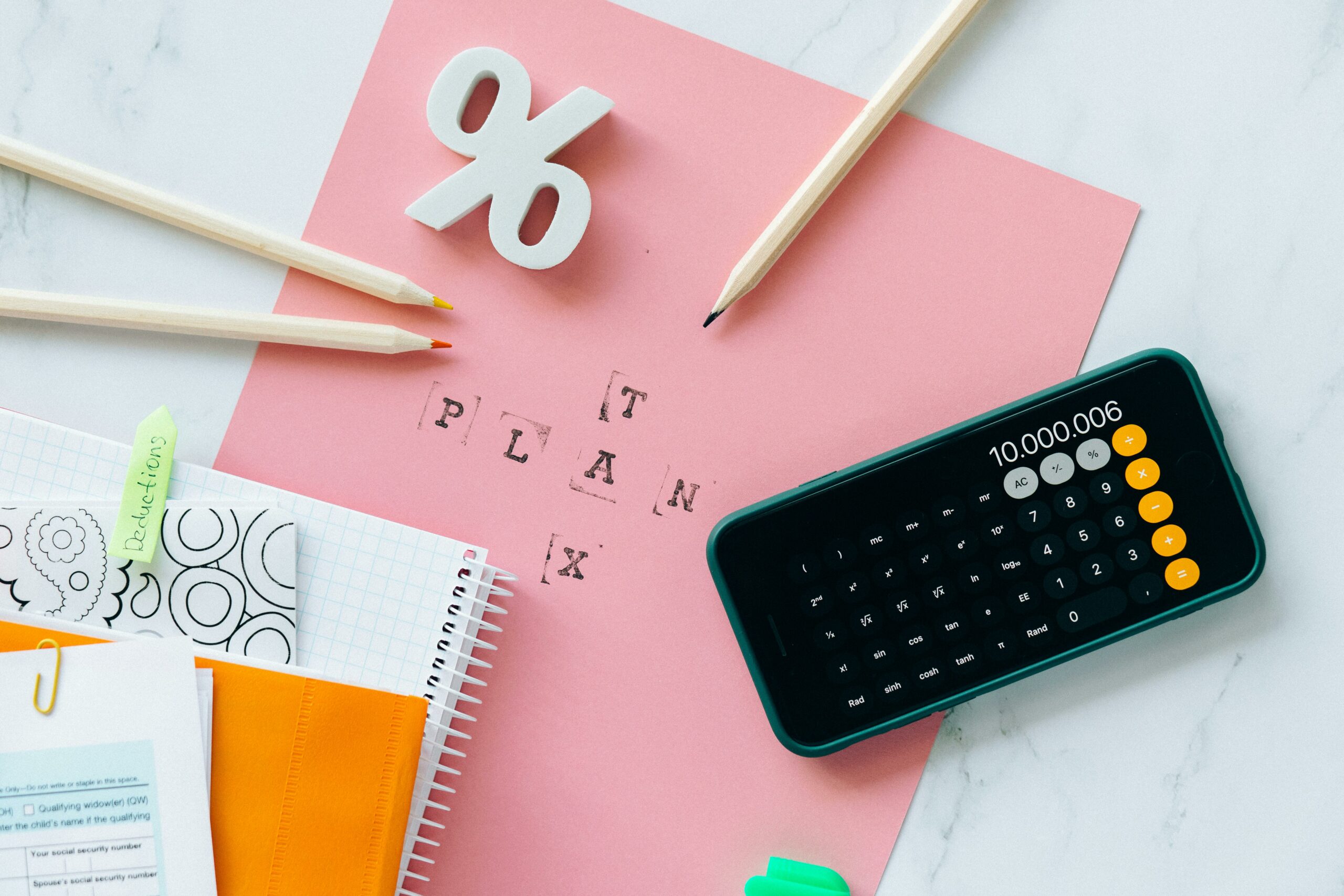 A pink piece of paper that says "tax" and "plan" with a phone calculator open.