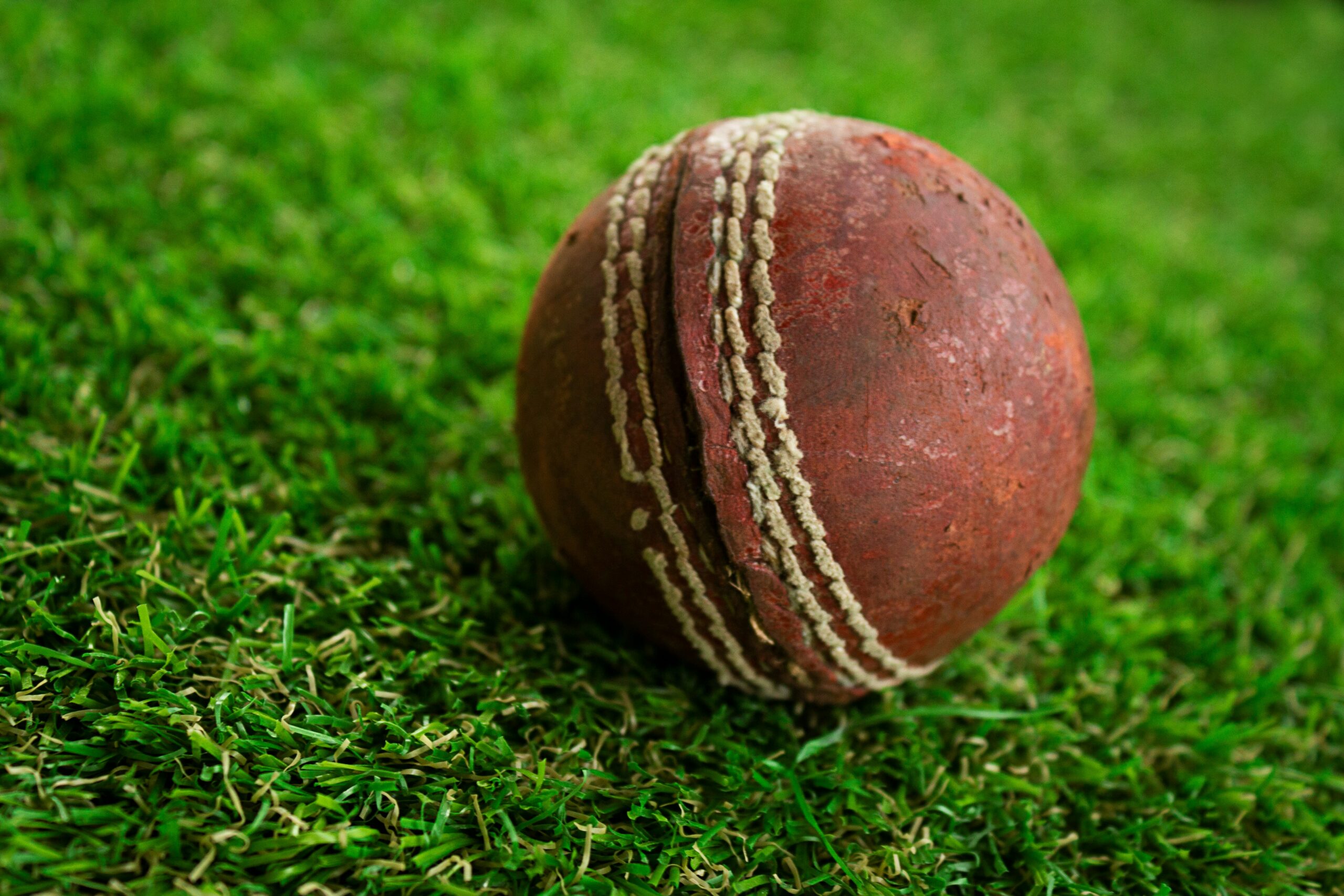 A cricket ball on a grass pitch
